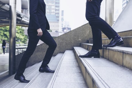 Photo: Two men in suits walking on stairs.