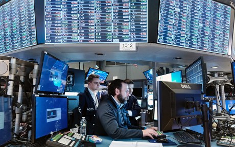 Photo: decorative: traders at a desk at the NY Stock exchange with a stock price board lit up above their heads