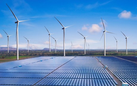 Photo: windmill farm with solar panels on the ground around them; story about climate change and bank risk.