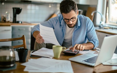 Decorative image: Man holding a piece of paper working on a calculator.