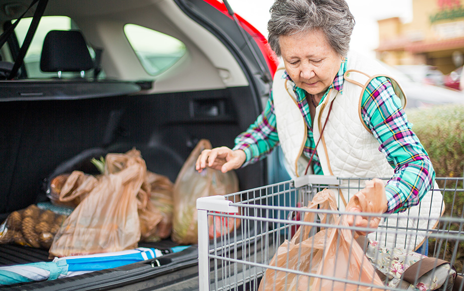 Decorative image: Woman loading groceries into trunk of car