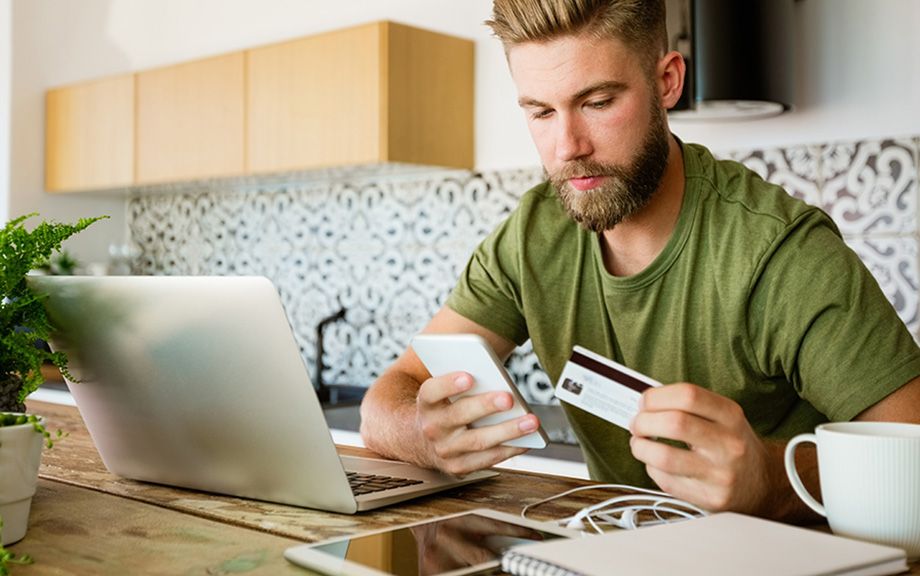 Decorative Image: Male at kitchen table with credit card and phone in hands
