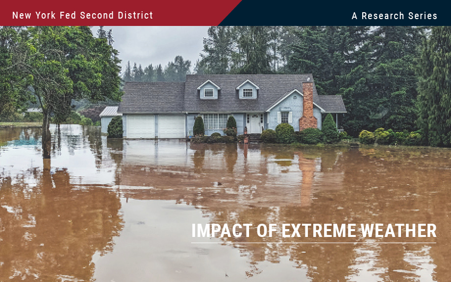 Photo of blue house in pine woods area flooded with muddy water up to its front door.