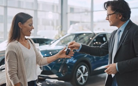 Decorative image: Woman receiving the keys to a car from a car dealership.