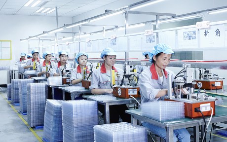 Photo: workers sitting at machines at a factory in China