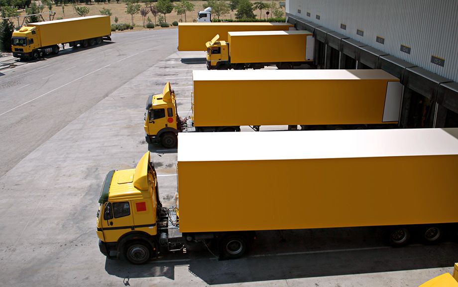 Photo: several yellow trucks backed into a loading dock