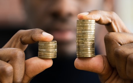 Imagem decorativa: Homem afro-americano segurando moedas na mão, mostrando disparidade monetária.