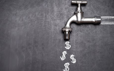Decorative photo of silver spigot on blackboard with dollar signs chalked on the board coming out of the spigot.