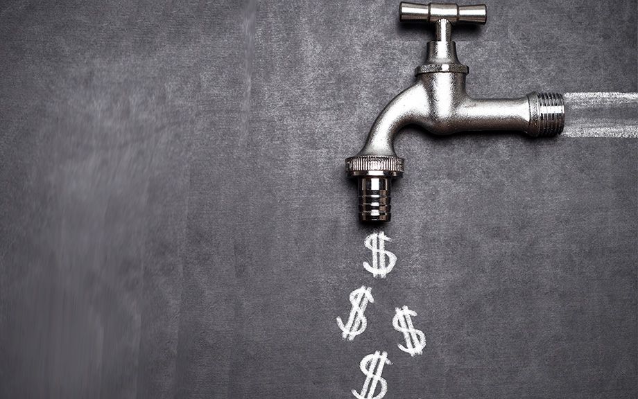 Decorative photo of silver spigot on blackboard with dollar signs chalked on the board coming out of the spigot.
