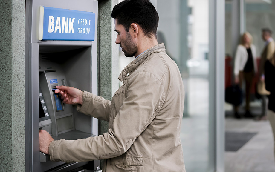 Photo of a caucasian male at Bank ATM machine.