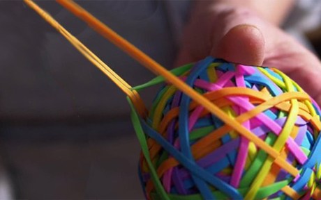 Decorative image: Man pulling an orange rubber band, holding a rubber band ball