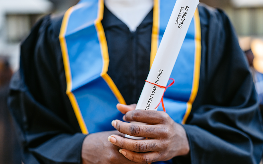 Decorative photo: Young Male Decorative photo: Student In Graduation Gown holding a student loan invoice as the rolled up degree