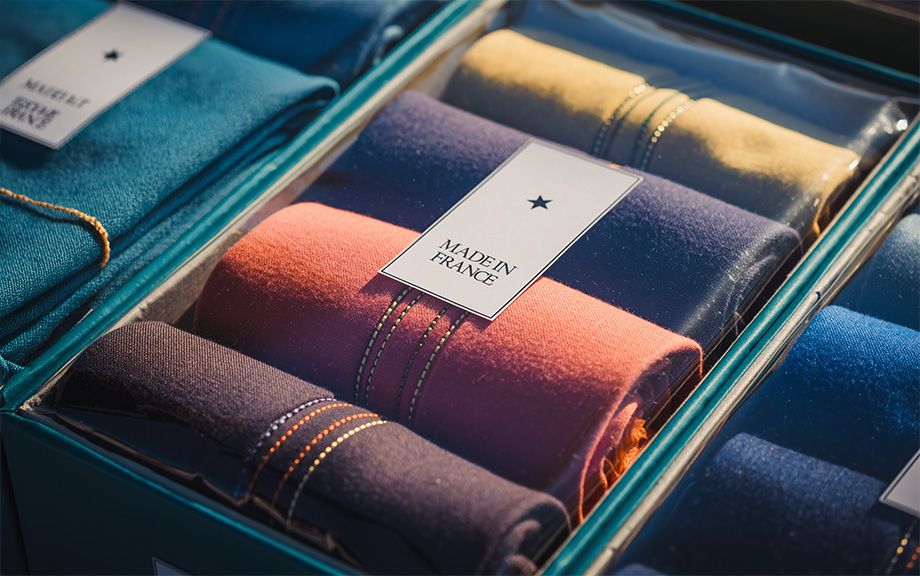 Photo: clothing items rolled in a box with label on it Made in France. AI generated