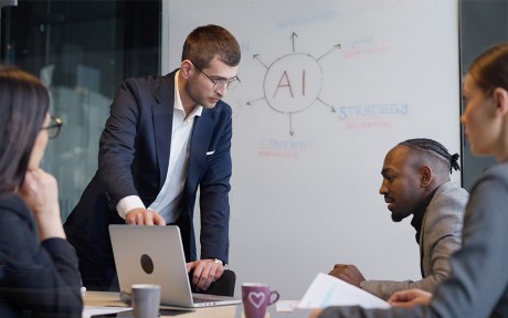 Image of workers in business suits being trained in AI through whiteboard and computer screen