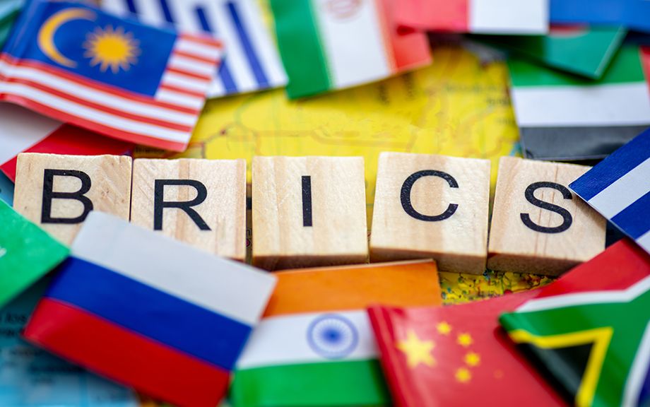 A Brics concept with wooden letter tiles and country flags on a map of Brazil.