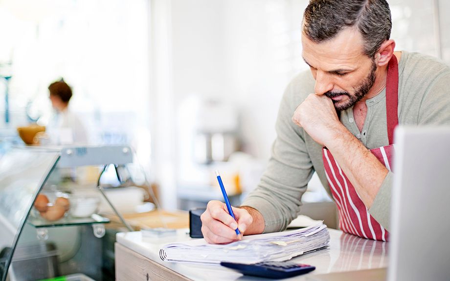 Small Business owner calculating at the counter of his cafe.