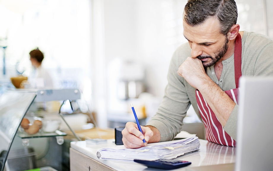 Small Business owner calculating at the counter of his cafe.