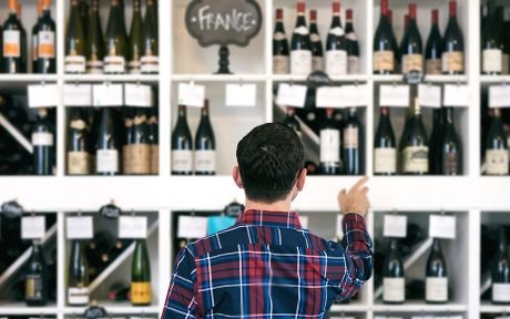 Owner/salesperson and customers inside a small, local wine shop.