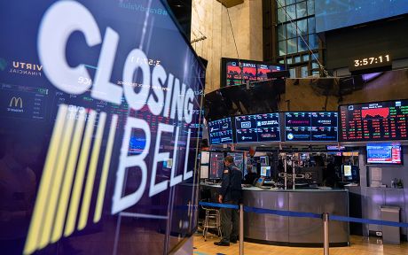 Floor of the stock exchange with a large screen in front that says closing bell.